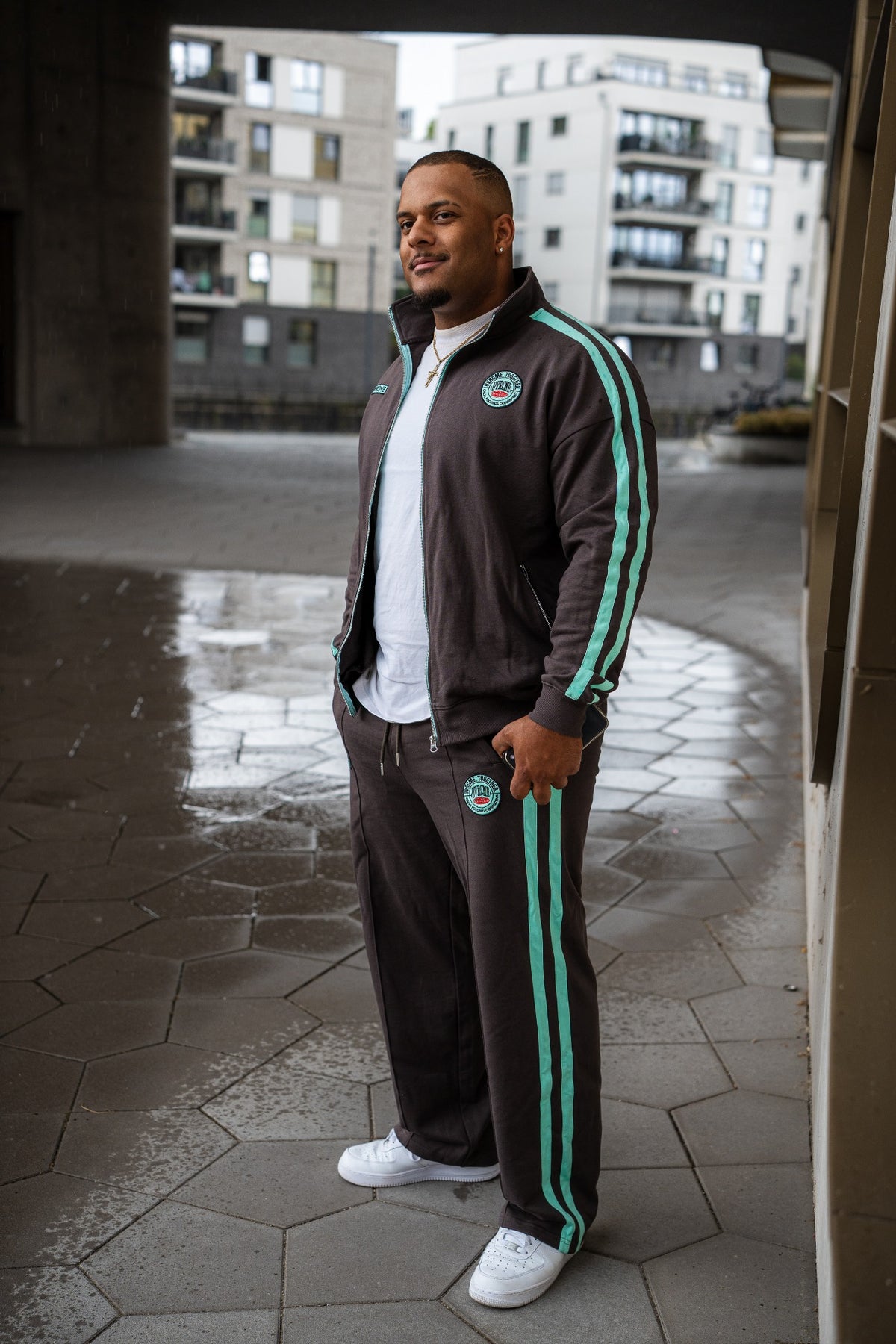 Jordan trägt den OVRCME CLUB Tracksuit in Anthrazit und Mint