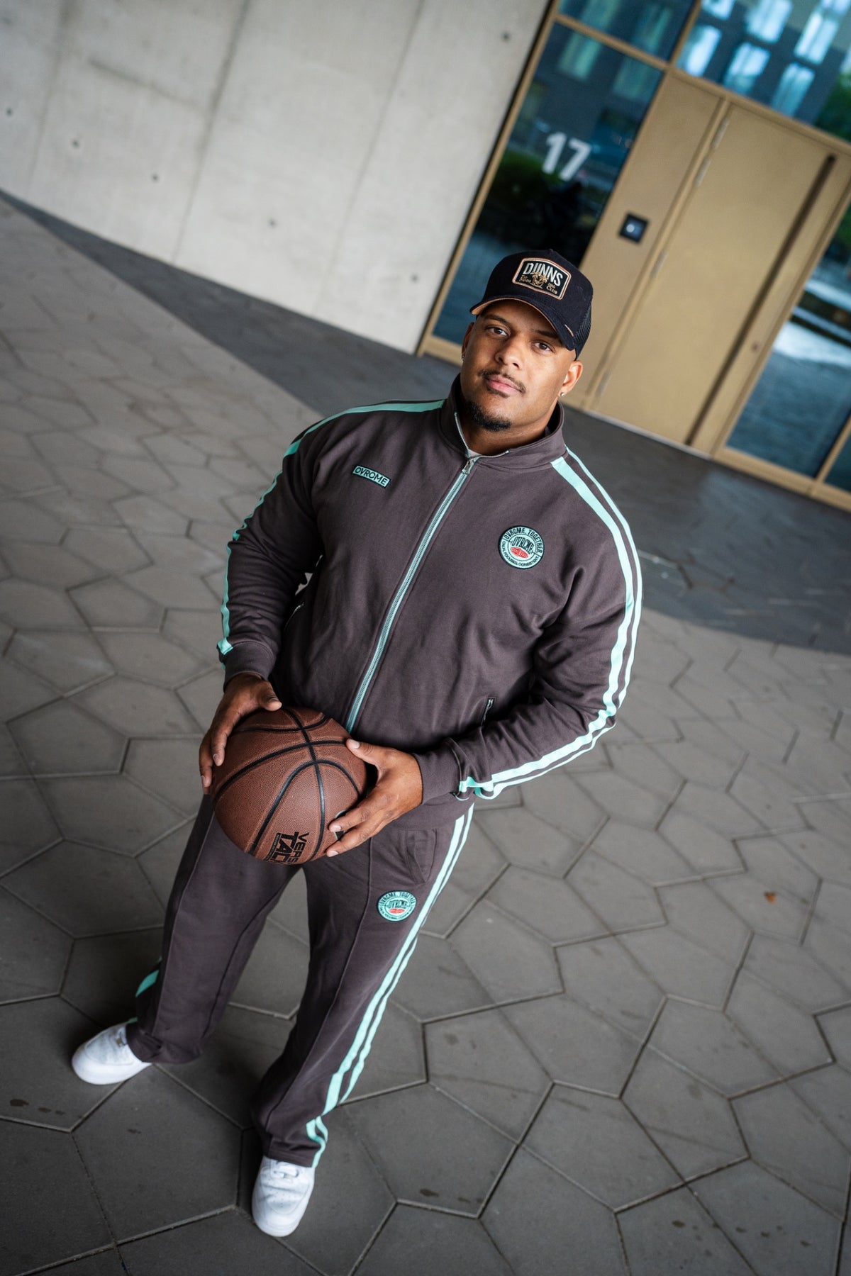OVRCME Tracksuit in Dunkelgrau mit mintfarbenen Streifen, getragen mit Basketball